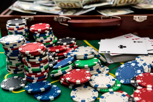 Suitcase with dollars, playing card, poker chips on the green poker table.