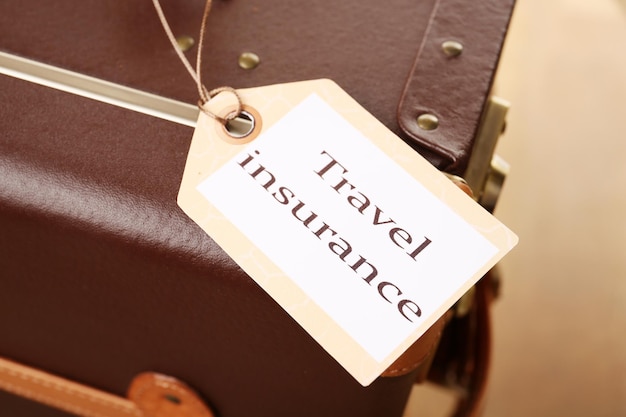 Photo suitcase with travel insurance label closeup