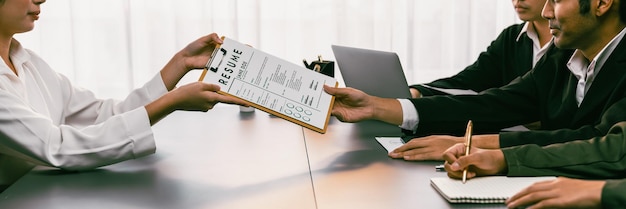 Photo suitclad candidate hand over resume to interviewers during job interview in meeting room job application and interview for career opportunity in modern office with hr recruitment team prodigy