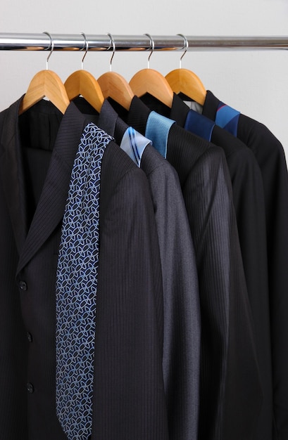 Suits and ties on hangers on gray background