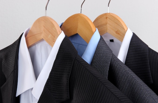 Suits with shirts on hangers on light background