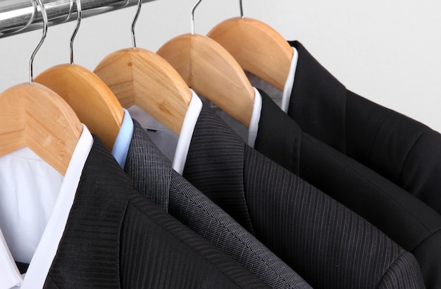 Suits with shirts on hangers on light background