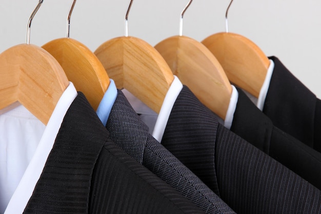 Suits with shirts on hangers on light background