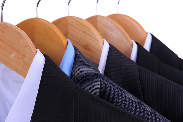 Suits with shirts on hangers on white background