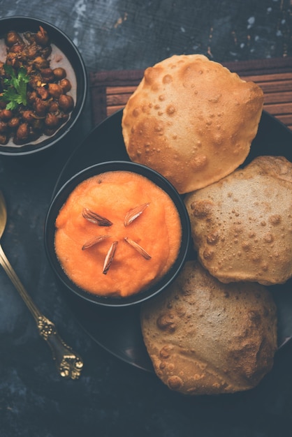 Suji or Sooji Halwa Puri or Sheera or Shira Poori breakfast, served in a plate and bowl. selective focus