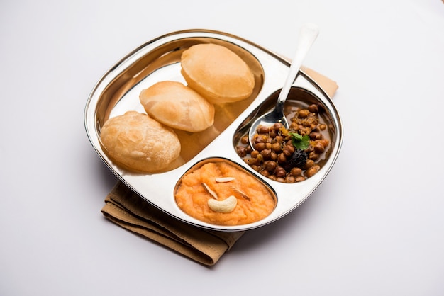 Suji or Sooji Halwa Puri or Sheera or Shira Poori breakfast, served in a plate and bowl. selective focus