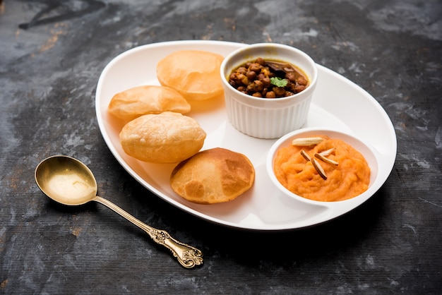 Suji or Sooji Halwa Puri or Sheera or Shira Poori breakfast, served in a plate and bowl. selective focus