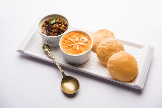 Suji or Sooji Halwa Puri or Sheera or Shira Poori breakfast, served in a plate and bowl. selective focus