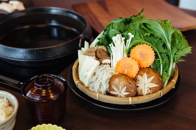 Набор овощей Сукияки, включая капусту, ложный пак чой, морковь, шиитаке, энокитаке и тофу.
