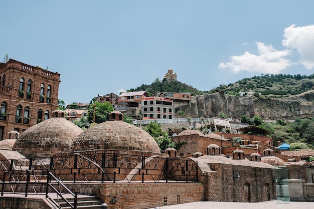 Photo sulfur baths in the old town in tbilisi georgian houses against the background of the fortress narikala city landscape georgia