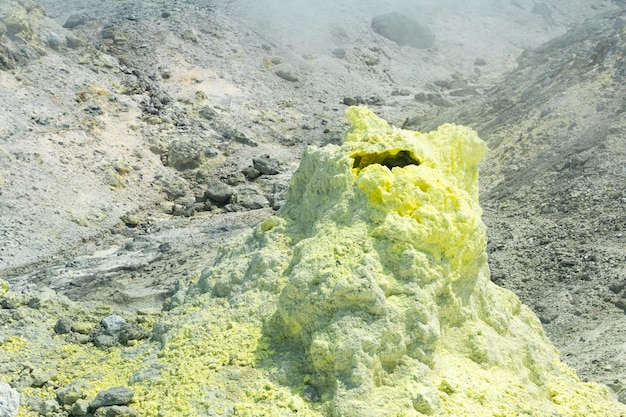 Sulfur deposits around a solfatara in a fumarole field on the slope of a volcano