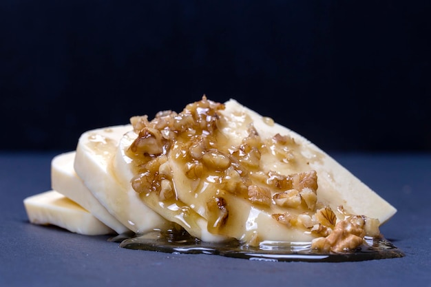 Suluguni cheese walnut and honey on black slate platter background close up