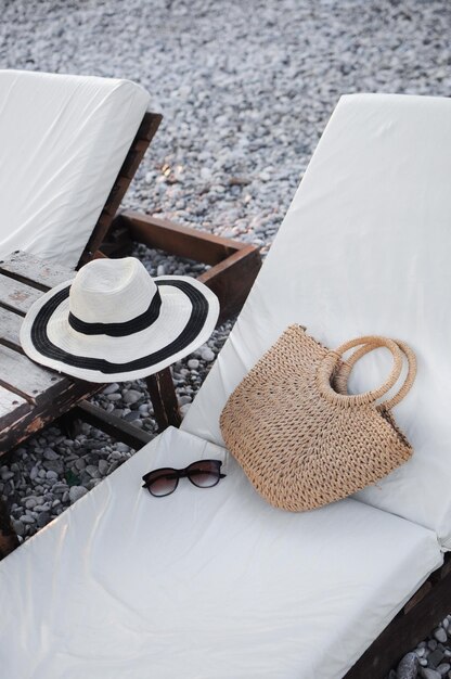 Summer accessories straw hat summer bag and sunglasses on a sunbed on beach