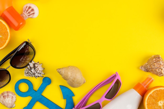 Summer accessories with shells, sun glasses, orange and coconut on a bright yellow background. top view.