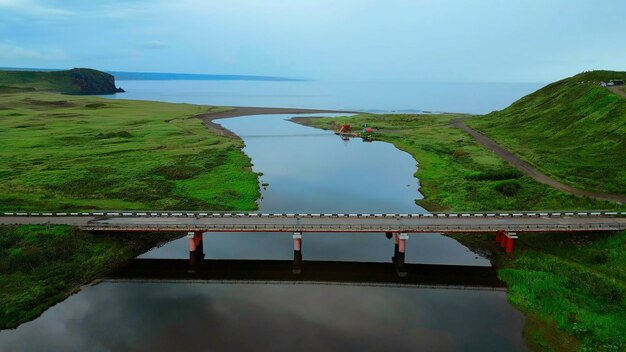 Фото Летний воздушный вид узкой реки, впадающей в море, бетонный мост, пересекающий спокойную реку