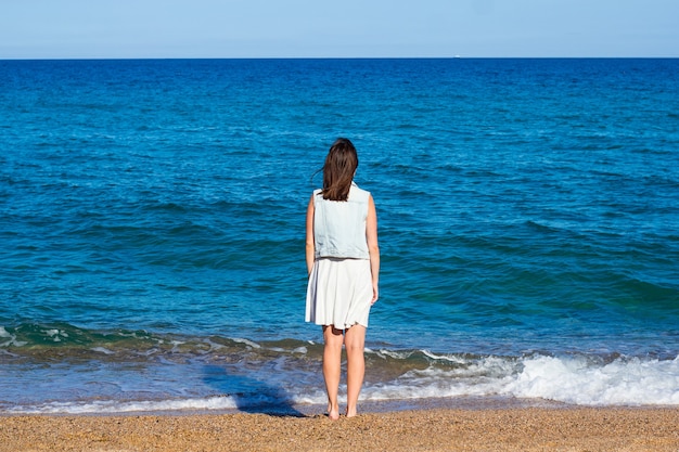 Фото Концепция лета и путешествий - вид сзади женщины, стоящей на пляже