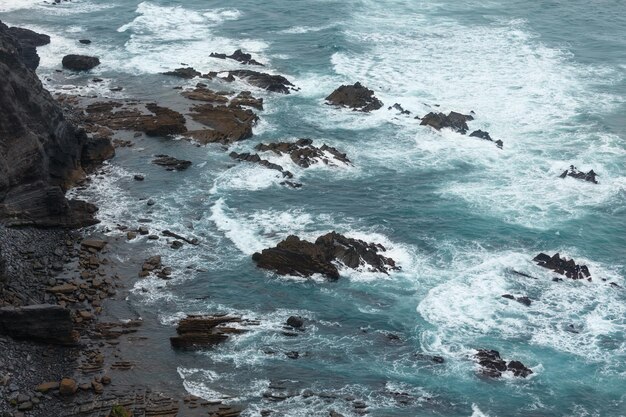 海の波の波と夏の大西洋の岩の多い海岸の景色（コスタビセンティーナ、アルガルヴェ、ポルトガル）。