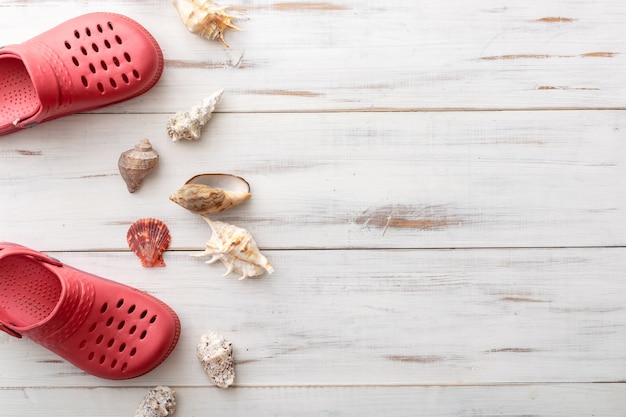 Summer background concept crocs, seashells, on light wooden surface