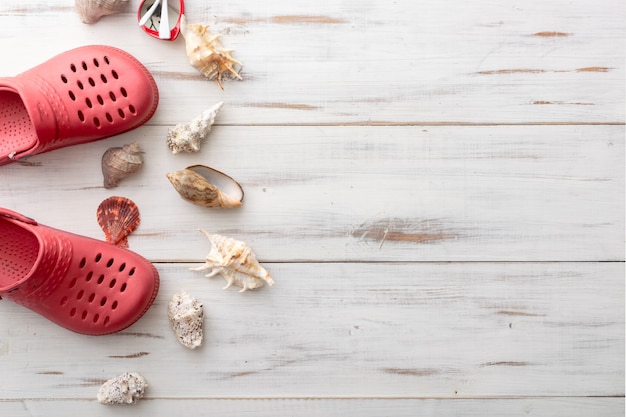 Summer background concept crocs, seashells, on light wooden surface