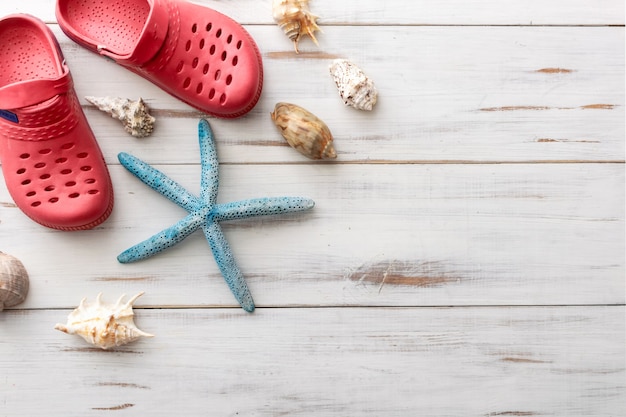 Summer background  concept crocs, starfish, seashells on light wooden surface