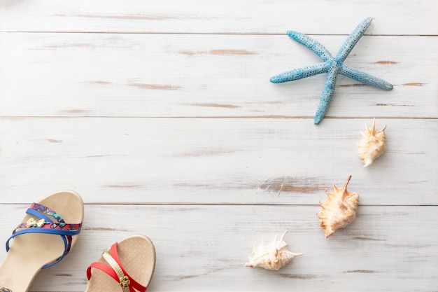 Summer background concept female sandals, seashells, starfish on light wooden surface