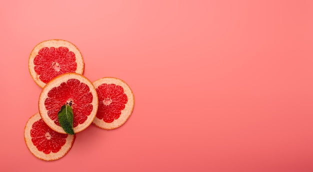 Summer background concept sliced grapefruit, mint on pink background