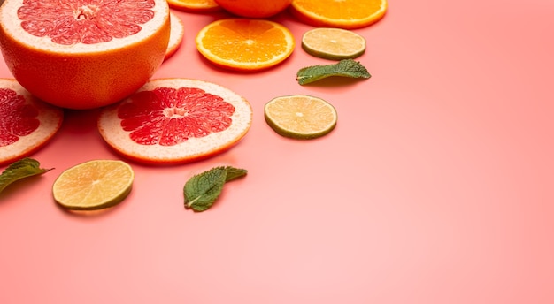 Summer background concept sliced orange, grapefruit, lemon, lime, mint on pink background