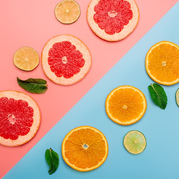 summer background concept sliced orange, grapefruit, lemon, lime on pink and blue background