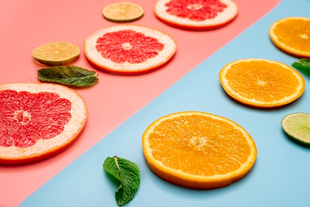summer background concept sliced orange, grapefruit, lemon, lime on pink and blue background