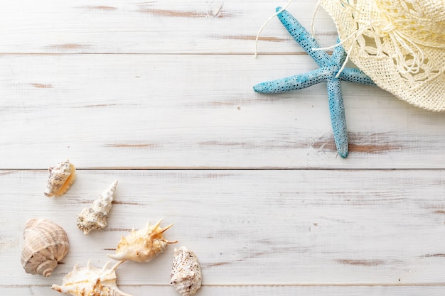 Summer background concept starfish, seashells, straw hat on light wooden surface 