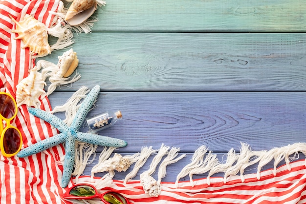 Foto sfondo estivo parei sfrangiati, conchiglie, occhiali da sole, stelle marine su uno sfondo di legno blu