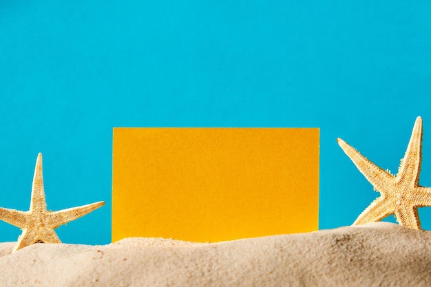 Фото Летний фон на песке, украшенный морскими звездами и желтым пространством для копирования