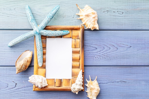 Summer background photo frame, starfish, seashells on a blue wooden background