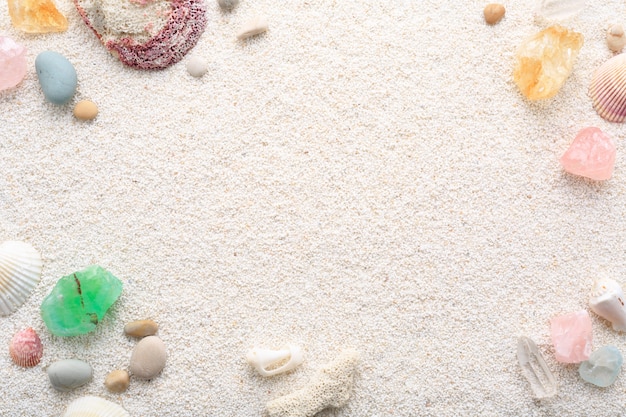 Summer background of seashells and sea pebbles on beach sand.