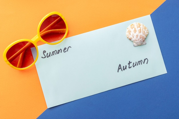 Photo summer background of shell, envelope with the inscription summer autumn on orange-blue background