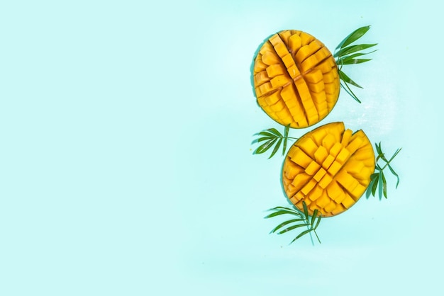 Летний фон с манго и пальмовыми листьями Свежие целые и нарезанные спелые плоды манго на ярко-бирюзовом фоне