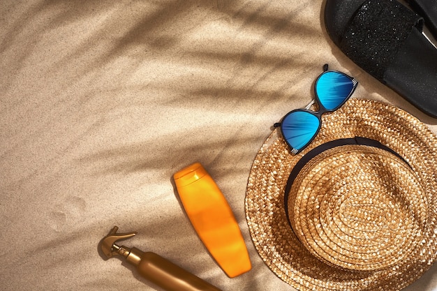 Summer background with straw hat sunglasses sunscreen bottle and flip flops