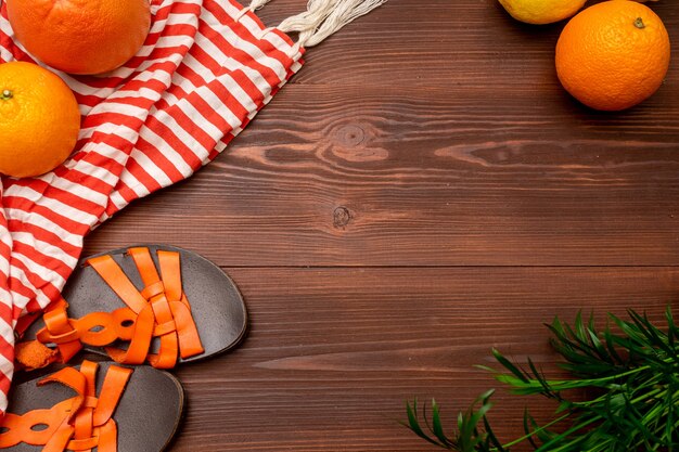 Summer background of women's sandals, pareo, orange, grapefruit, palm on a wooden surface