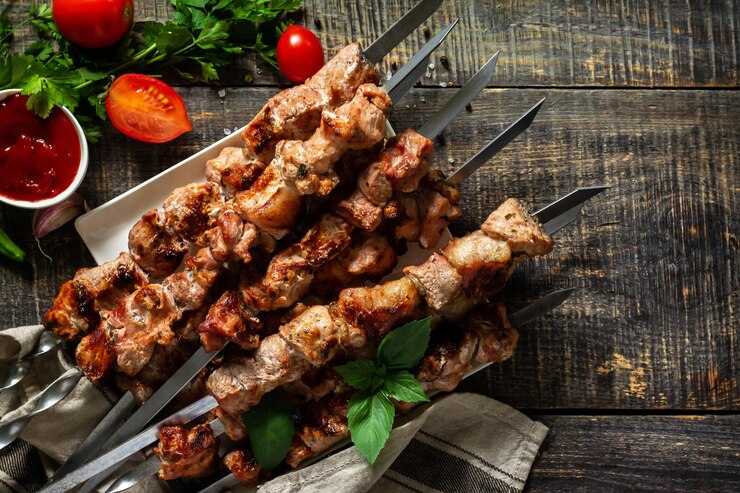 夏のバーベキューメニュー素朴な木製のテーブルで焼いた肉の串焼き上面図コピースペース