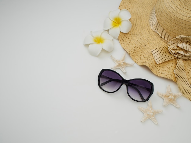 Summer beach dress items - shells, starfish, sunglasses, straw hats on a white background 