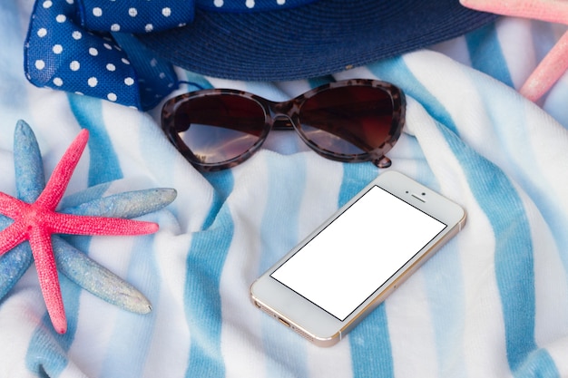 Summer beach towel, starfish and hat, copy space  on phone with blank screen