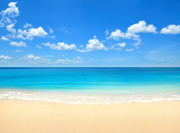 Foto spiaggia estiva con sfondo blu cielo e nuvole.