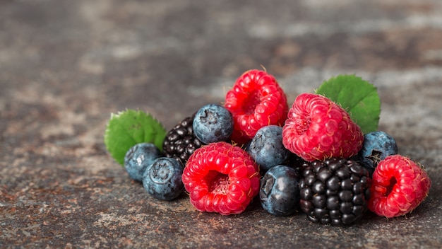 summer berries mix with raspberry, blueberry and blackberry on dark background