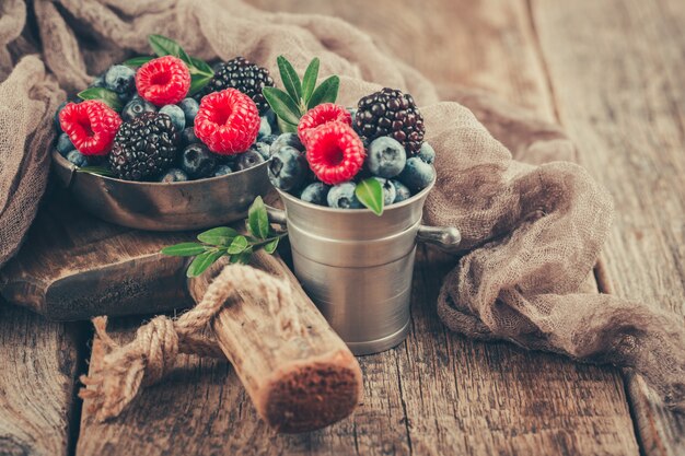 Summer Berries mix with Raspberry, Blueberry and Blackberry in metal dishes on wood background