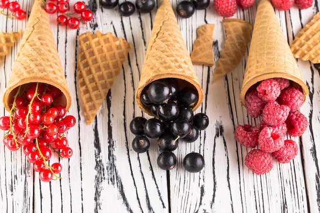 Summer berries in waffle cone on wooden background