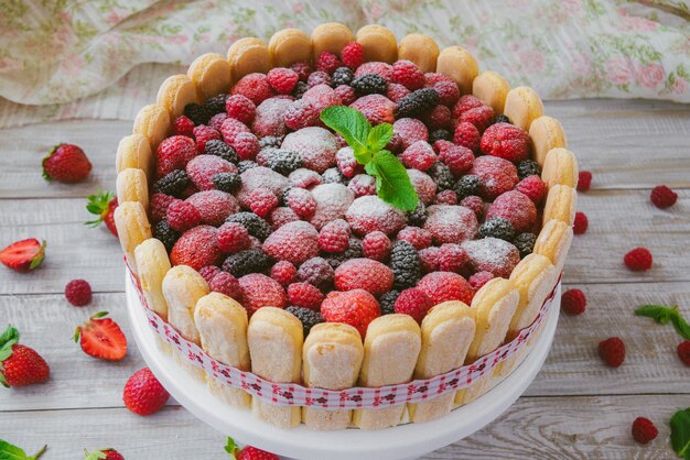 The summer biscuit naked bargaining with cream of mascarpone and fresh berries on a wooden surface