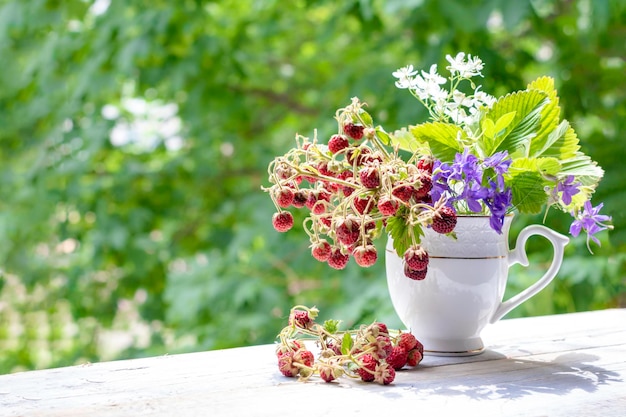 Bouquet estivo di fragoline di bosco e fiori di campo sul davanzale