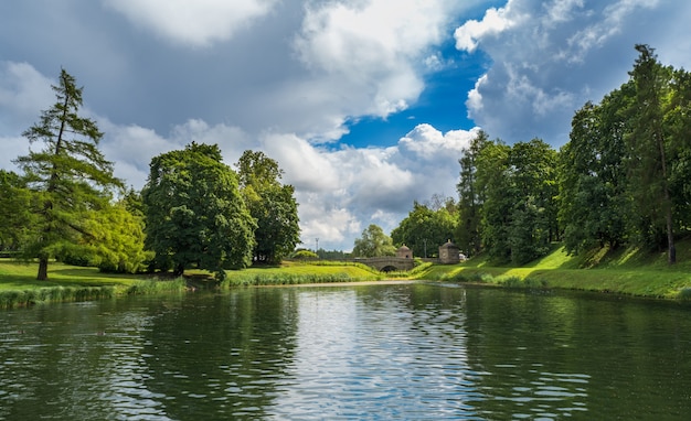 Summer bright landscape with a lake, greenery and clouds.