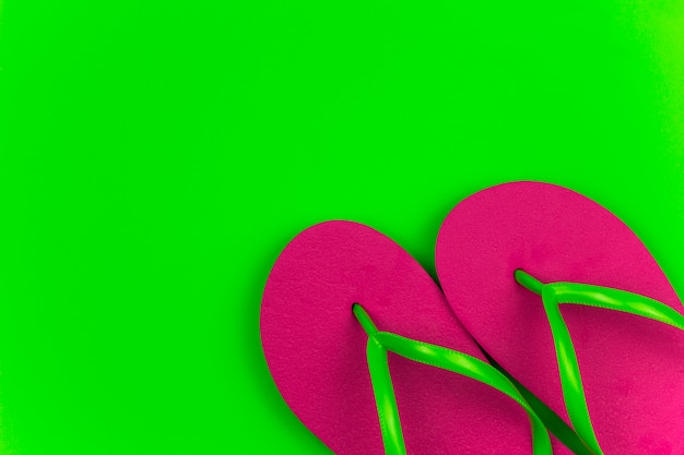 Summer bright pink flip flops green background