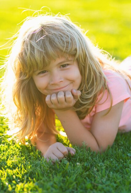 Summer child face smiling child boy with grass background child in park outdoor spring kid lying on